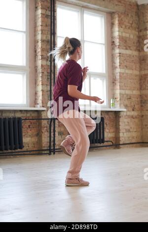 Rear view of young dancer in sports clothing dancing alone in dance studio Stock Photo