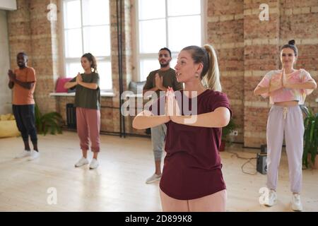 Young instructor showing the exercises to the group during yoga class in health club Stock Photo