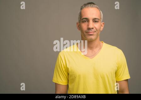 Handsome Persian man with gray hair against gray background Stock Photo