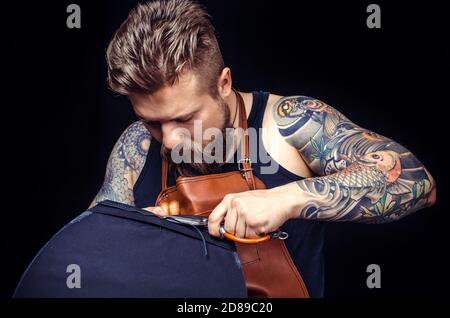 Worker of leather producing leather workpiece at his workshop Stock Photo