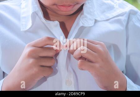 Close up of a little boy learning get dressed, buttoned white shirt and get ready for school, Early Education concept. Stock Photo