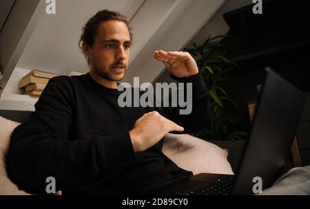 Young caucasian male preparing for online video call with lecturer of university watching laptop sitting in relaxed bedroom  Stock Photo