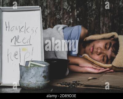 Hungry child lay down on street with hungry and asking help food or money from traveler on street at the city. Unidentified homeless child begging on Stock Photo