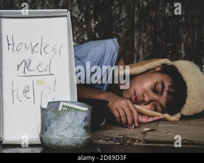 Hungry child lay down on street with hungry and asking help food or money from traveler on street at the city. Unidentified homeless child begging on Stock Photo