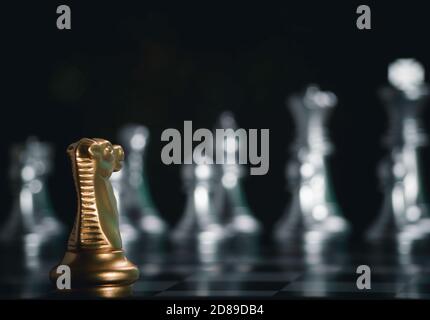 Golden knight chess pieces facing in front silver chess on board with flare light to successfully in the competition. Management or leadership strateg Stock Photo