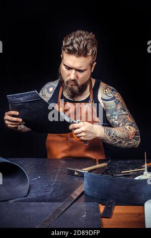 Currier of leather producing leather workpiece in workplace Stock Photo