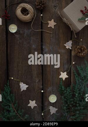 Christmas and New Year composition with fir branches, candles, gift box, wooden christmas toys. Rustic wood background, copy space. Stock Photo