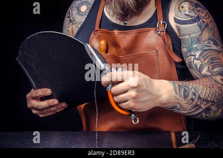 Currier of leather working with leather using crafting tools in his tanning shop Stock Photo
