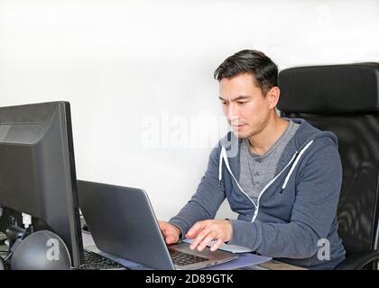 Man in casual outfit working from home with a laptop in the living room Stock Photo