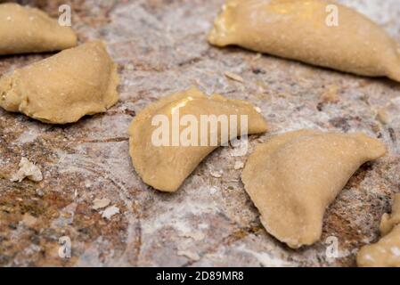 Dumplings with cottage cheese in the process of making and preparing for cooking. Homemade food, Polish cuisine. Raw dough on the table. Stock Photo