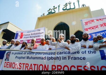Muslim protesters display placards and hold a banner during the protest against French president Emmanuel Macron in Dhaka.Thousands of Muslim protesters hold a march calling for the boycott of French products and denouncing French president Emmanuel Macron for his remarks ‘not to give up cartoons depicting Prophet Mohammed’. Macron's remarks came in response to the beheading of a teacher, Samuel Paty, outside his school in a suburb outside Paris earlier this month, after he had shown cartoons of the Prophet Mohammed during a class he was leading on free speech. Stock Photo