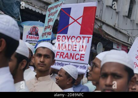 A Muslim protester is seen holding  up a placard to Boycott all French products during the demonstration against the French President in Dhaka.Thousands of Muslim protesters hold a march calling for the boycott of French products and denouncing French president Emmanuel Macron for his remarks ‘not to give up cartoons depicting Prophet Mohammed’. Macron's remarks came in response to the beheading of a teacher, Samuel Paty, outside his school in a suburb outside Paris earlier this month, after he had shown cartoons of the Prophet Mohammed during a class he was leading on free speech. Stock Photo