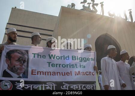 Protesters from Islami Oikya Jote, an Islamist political party, hold banner reading 'The World Biggest terrorist Emmanuel Macron' during the protest in Dhaka.Thousands of Muslim protesters hold a march calling for the boycott of French products and denouncing French president Emmanuel Macron for his remarks ‘not to give up cartoons depicting Prophet Mohammed’. Macron's remarks came in response to the beheading of a teacher, Samuel Paty, outside his school in a suburb outside Paris earlier this month, after he had shown cartoons of the Prophet Mohammed during a class he was leading on free spee Stock Photo