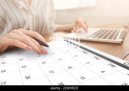 Business Scheduling. Unrecognizable Woman Working On Laptop And Checking Calendar At Workplace Stock Photo
