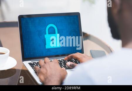 Man typing on laptop keyboard, padlock icon on the screen Stock Photo
