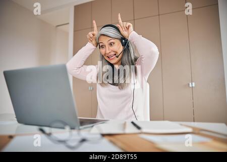 Funny woman talking on video call while sitting at the desk in room indoors Stock Photo