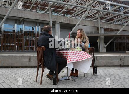 Pierre Levicky owner of Chez Jules restaurant in Edinburgh alongside Kasia Panisco as they stage a protest by having a meal outside the Scottish Parliament in Edinburgh after a range of new restrictions to combat the rise in coronavirus cases came into place in Scotland. Stock Photo