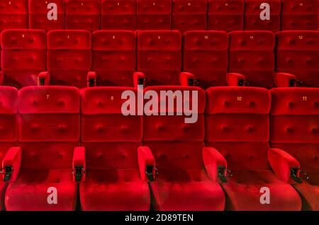 Empty comfortable red seats with numbers in the hall of the cinema or theate Stock Photo