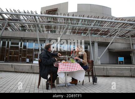 Pierre Levicky owner of Chez Jules restaurant in Edinburgh alongside Kasia Panisco as they stage a protest by having a meal outside the Scottish Parliament in Edinburgh after a range of new restrictions to combat the rise in coronavirus cases came into place in Scotland. Stock Photo