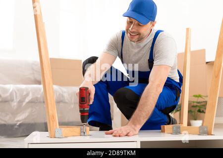 Professional Craftsman Carpenter Assembling Table Using Electric Drill Working Indoor Stock Photo