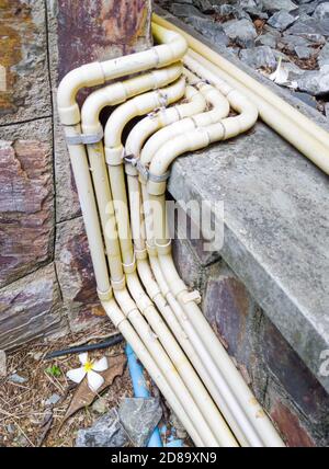 Yellow electrical conduit row with the metal clamp along the tile floor for the electrical system in the restaurant. Stock Photo