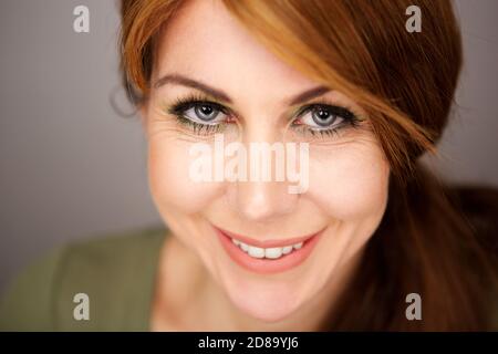 Close up portrait of attractive mature woman with beautiful gray eyes smiling at camera Stock Photo