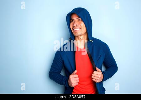 Portrait of mature asian man in hooded sweatshirt against blue wall Stock Photo