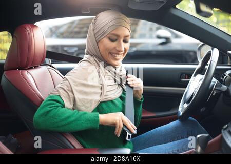 Muslim Woman In Hijab Putting On Seat Belt Stock Photo