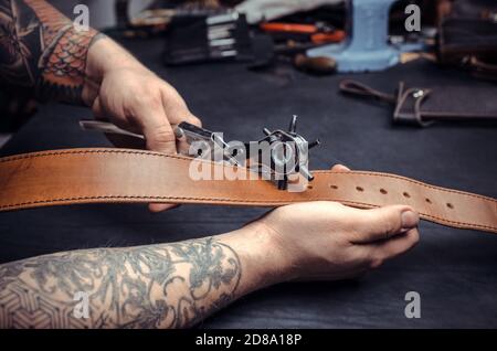 Artisan demostrating leather cutting process at his work area Stock Photo