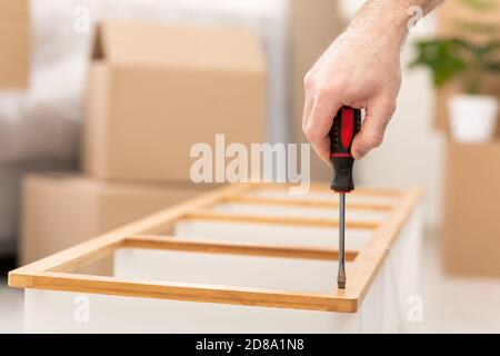 Unrecognizable Man Assembling Cabinet Shelf Using Screwdriver Tool Indoors, Cropped Stock Photo