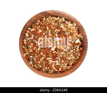 Mix of herbs, spices and dry tomatoes in wooden bowl, isolated on white background. Natural organic food seasoning. Top view. Stock Photo