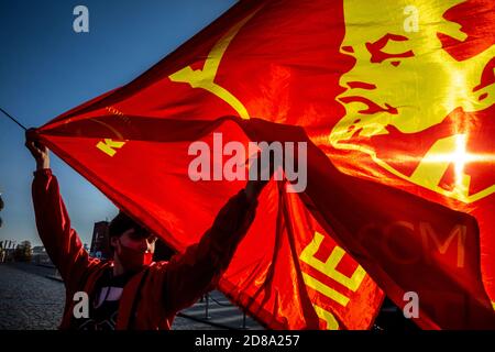 Moscow, Russia. 28th of October, 2020 A supporter of the communist party holds a Red flag with Komsomol badge as other gather at Red Square to mark the 102nd anniversary of Komsomol, or the All-Union Leninist Young Communist League, the Soviet-era communist youth organization, in Moscow, Russia Stock Photo
