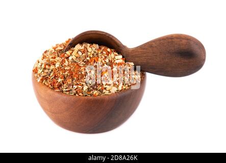 Mix of herbs, spices and dry tomatoes in wooden bowl and spoon, isolated on white background. Natural organic food seasoning. Stock Photo
