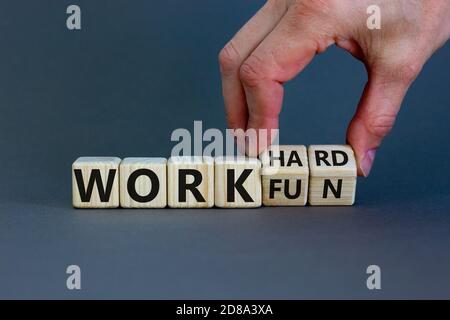 Hand turns a cubes and changes the expression 'work hard' to 'work fun' or vice versa. Beautiful grey background. Business concept, copy space. Stock Photo