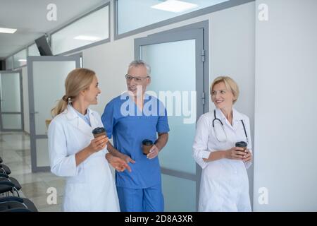Group of professional medical workers enjoying coffee in the corridor Stock Photo