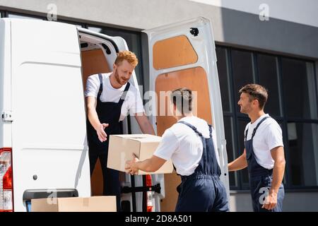Movers unloading cardboard boxes from truck on urban street Stock Photo