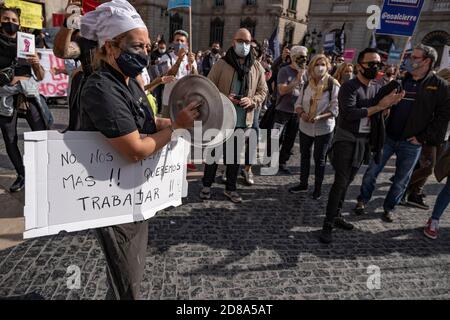 Barcelona, Spain. 28th Oct, 2020. A protester wearing a chef's hat and face mask is seen applauding with two pot lids during the demonstration.Professionals, businessmen and workers of restaurants, bars and nightlife venues demonstrate against the restrictive measures taken by the Government as a result of the increases in Covid infections that forces them to remain closed with a poor economic rescue. Credit: SOPA Images Limited/Alamy Live News Stock Photo