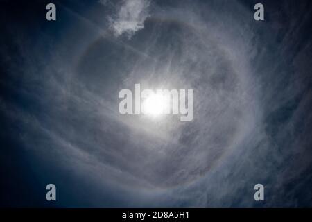 Low angle view of bright sun with halo effect and wispy clouds. Stock Photo
