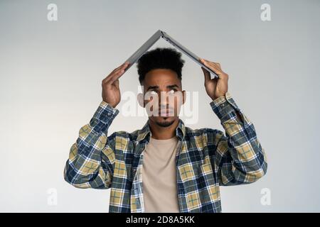 Frustrated entrepreneur is carrying a laptop over his head. Isolated on white background. Stock Photo