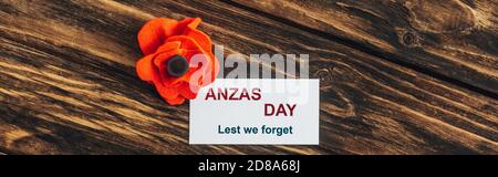 panoramic shot of card with anzas day lettering near artificial flower on wooden surface Stock Photo