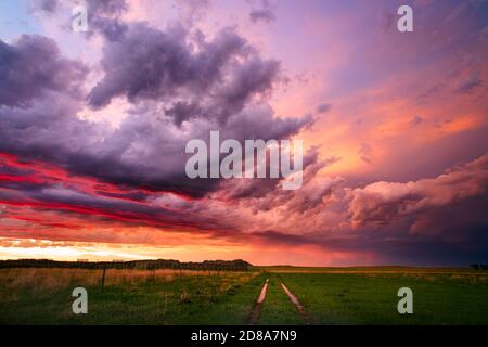 A colorful sunset sky emerges behind a departing storm over a scenic South Dakota landscape near Camp Crook. Stock Photo