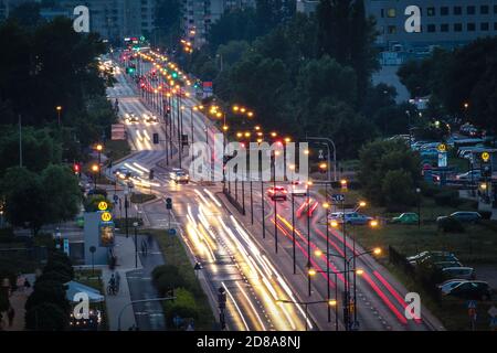 Wide street in residential district of Warsaw in evening with motion blurred lights of cars Stock Photo