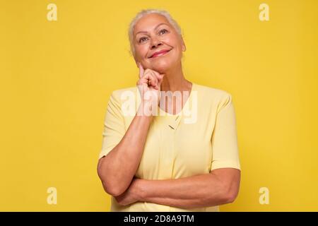 Elderly pretty woman standing daydreaming or reminiscing looking up Stock Photo