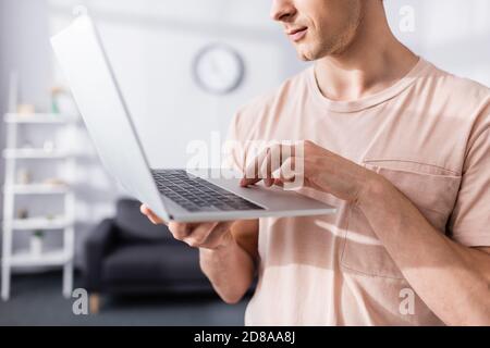 Cropped view of freelancer holding and typing on laptop at home, earning online concept Stock Photo