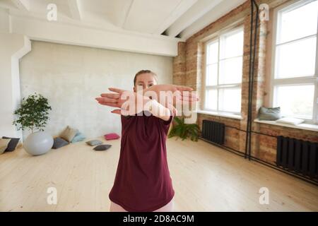 Portrait of young woman showing dance exercises to the camera while standing in dance studio Stock Photo