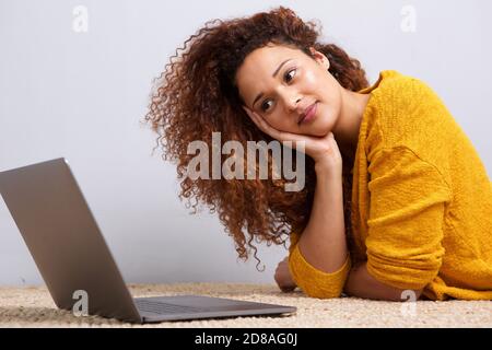 Portrait of african american girl lying on floor looking at laptop computer screen Stock Photo
