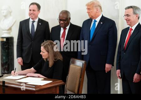 Supreme Court Associate Justice Amy Coney Barrett signs the oath certificate Monday, Oct. 26, 2020, in the Cross Hall of the White House as President Donald J. Trump, Supreme Court Associate Justice Clarence Thomas, White House Counsel Pat Cipollone, and Staff Secretary Derek Lyons observe from behind. (USA) Stock Photo