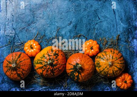 Pumpkins on a blue dark stone background. Concept autumn, halloween, harvest. Banner. Flat lay, top view. Stock Photo