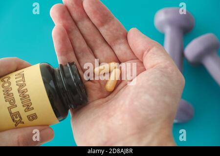 Person taking out Vitamin B Complex pills out of a bottle. Close up. Stock Photo
