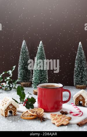 Christmas cappuccino in red mug on grey table with gingerbread cookies and other Christmas decorations. Merry Christmas greeting card. Stock Photo